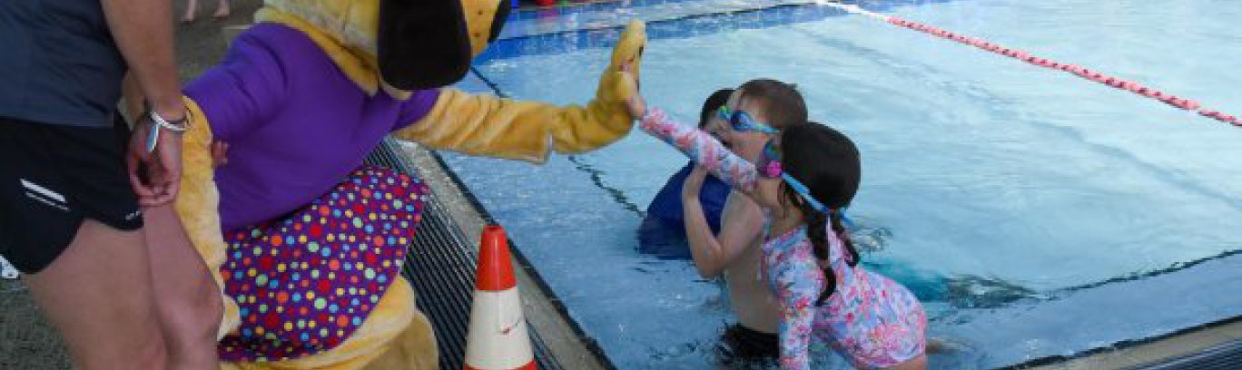kids in pool high fiving a person in a costume