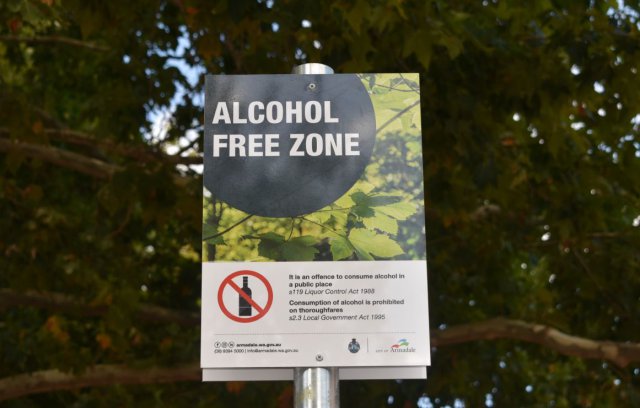 Image of alcohol free zone information on metal sign on pole