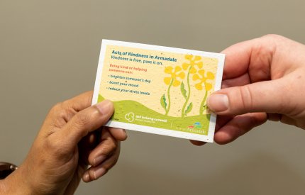 two hands holding an act of kindness card