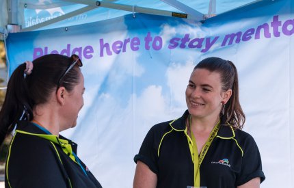 Two people smiling at each other under a mental health banner