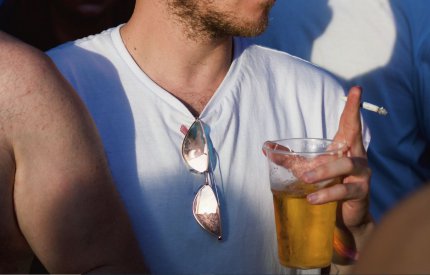 person holding cigarette and cup of alcohol