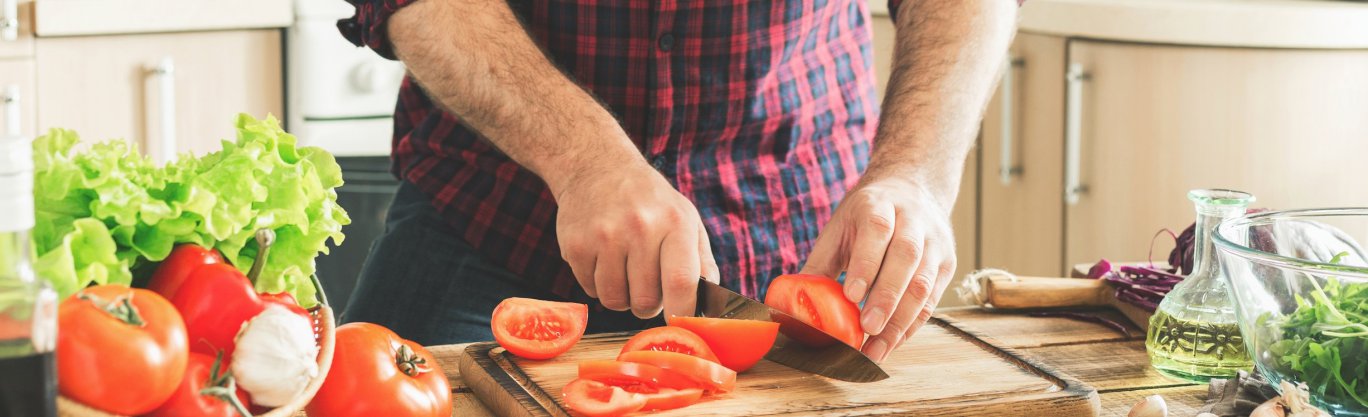 image of food preparation - man chopping tomatoes